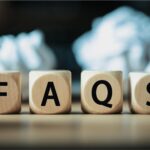 Wooden blocks spelling ‘FAQS’ placed on a desk, representing frequently asked questions related to GST compliance, tax updates, and regulatory guidance.